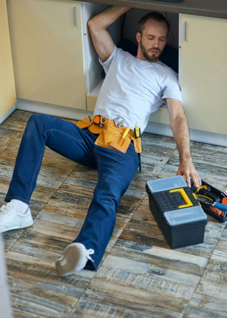 Plumbing expert. Professional repairman, plumber wearing tool belt examining and fixing sink pipe in